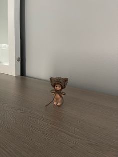 a small doll sitting on top of a wooden floor next to a white painted wall