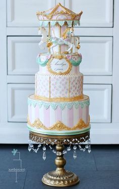 a three tiered cake with gold trimmings and pink and white striped icing