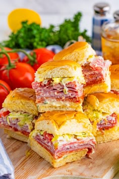 a pile of sandwiches sitting on top of a wooden cutting board