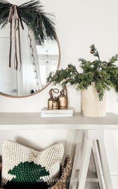 a white table topped with a mirror next to a potted plant and other items