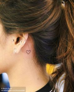 a woman wearing ear piercings with a heart tattoo on her left side of the ear