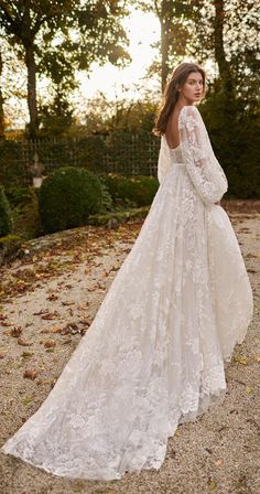 a woman in a wedding dress standing on gravel