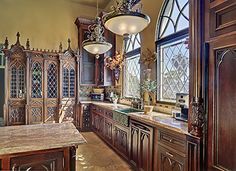 a large kitchen with wooden cabinets and marble counter tops, along with a chandelier hanging from the ceiling