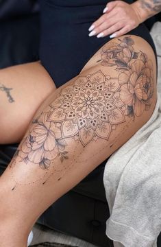 a woman's legs with tattoos on them and flowers in the middle of her leg