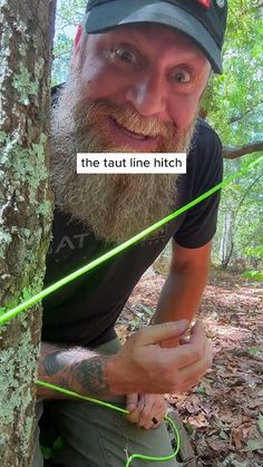 a man with a long beard is sitting next to a tree and holding a fishing line