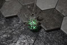 a green ball with an angel on it is sitting on a black tile floor next to a silver chain