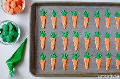 carrots on a baking sheet with green icing and candies in the background