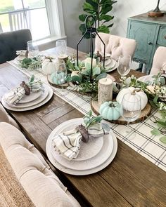 a dining room table set with plates and place settings