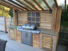 an outdoor kitchen is built into the side of a wooden building with stainless steel appliances