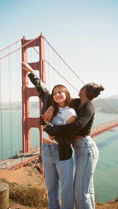 a man and woman standing in front of the golden gate bridge with their arms around each other