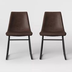 two brown chairs sitting side by side in front of a white background with black legs