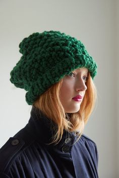 a woman with red hair wearing a green knitted beanie hat, looking off to the side