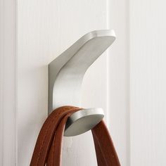 a pair of leather straps hanging on the side of a white door with a metal hook