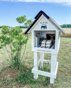 a small white bird house in the middle of a field