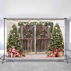 christmas trees and presents in front of an open wooden door with lights on the side