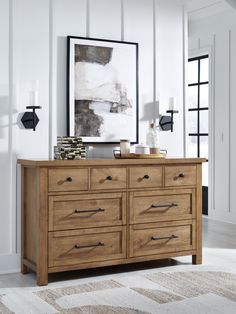 a large wooden dresser sitting on top of a white floor next to a painting and lamp