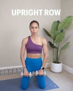 a woman standing on top of a blue yoga mat holding two white dumbbells