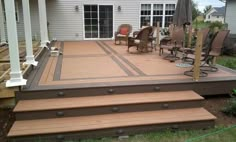 a deck with chairs and an umbrella in the middle of it next to a house