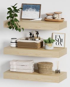 three wooden shelves with towels, plants and pictures on the top one shelf is filled with personal care items