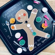 a child's play tray with spoons, measuring cups and a gingerbread man on it