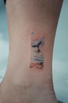 a small tattoo on the ankle of a woman with a whale tail coming out of the water