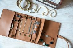 an open wallet sitting on top of a wooden table next to some bracelets and rings