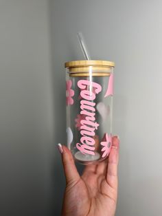 a person holding up a glass with pink butterflies on it