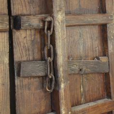 an old wooden door with a chain hanging from it