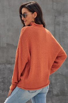 a woman wearing an orange sweater and jeans