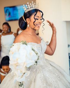 a woman wearing a tiara and holding a bouquet in front of her face with other women behind her