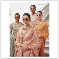 four women in sari standing next to each other on the steps with their arms crossed