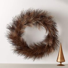 a brown wreath sitting on top of a table next to a gold cone