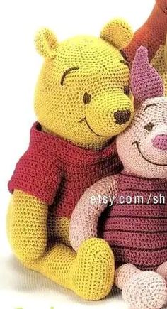 two crocheted winnie the pooh and piglet stuffed animals sitting next to each other