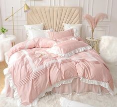 a bed with pink comforter and pillows in a room next to a white wall