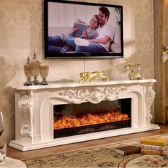 a man and woman sitting on a couch in front of a fireplace with a television above it