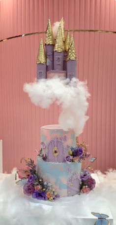 a three tiered cake with clouds and flowers on top