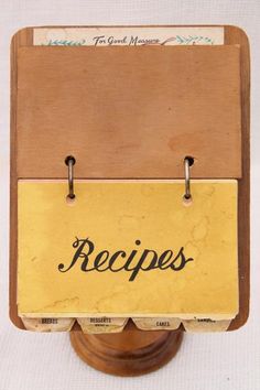 an old fashioned recipe book holder on a wooden stand with clippings attached to it