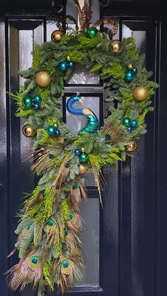 a wreath with peacocks and ornaments hanging on the front door to decorate it for christmas