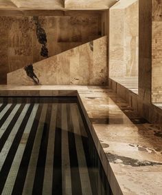 an indoor swimming pool in the middle of a room with stone walls and flooring