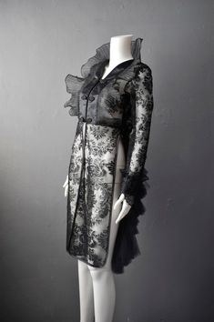 For every goth queen who dresses to impress, our 'Dark Sídhe' tailcoat is a lightweight sheer jacket with a gossamer light ruffled standing collar for an imposing gothic look!Made from a transparent floaty organza with a beautiful flocked velvet baroque damask pattern, this semi fitted jacket has a black satin front that fastens with hook and eyes, as well as decorative frog closures, plus two knee length tabards, while rows of fine bridal tulle at the back create a frothy bustled look.A great p Elegant Halloween Costume Outerwear, Elegant Long Sleeve Outerwear For Halloween, Black Sheer Long Sleeve Outerwear, Gothic Black Party Outerwear, Black Gothic Party Outerwear, Elegant Fitted Halloween Outerwear, Elegant Fitted Outerwear For Halloween, Victorian Black Outerwear For Costume Party, Sheer Long Sleeve Party Outerwear