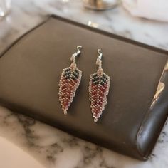 a pair of red, white and blue beaded earrings sitting on top of a table