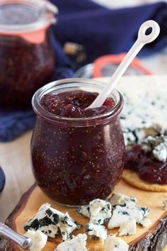 there is a jar of jam and crackers on the cutting board next to it