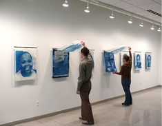 two people looking at paintings on the wall