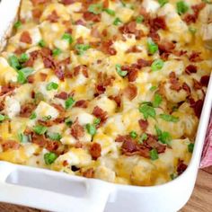 a casserole dish with bacon, cheese and green onions in it on a wooden table