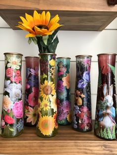 several vases with flowers painted on them are sitting on a shelf next to a sunflower