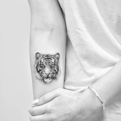 a person with a tiger tattoo on their arm and the other hand is holding an animal