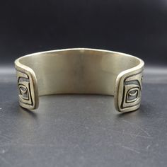 "VINTAGE KABANA BRACELET DESCRIPTION: This handsome bracelet is a vintage piece from Kabana, makers of fine southwestern jewelry since 1975. Images from the Pacific Northwest grace this heavy gauge sterling silver cuff. This bracelet will be a treasured addition to your collection of fine vintage Southwestern jewelry. MEASUREMENTS: Interior of the cuff measures 5 3/4\" with an additional 1 3/8\" non-adjustable gap. Total circumference: 7 1/8\" Measures 2 1/2\" straight across the widest part of Unique Adjustable Bracelets With Antique Finish, Unique Adjustable Bracelet With Antique Finish, Adjustable Bohemian Bracelet With Antique Finish, Adjustable Bracelet With Antique Finish, Southwestern Oxidized Adjustable Jewelry, Artisan Oxidized Bangle Jewelry, Vintage Gold Bracelets With Oxidized Finish, Antique Brass Collectible Bracelets, Collectible Handmade Bangle Jewelry