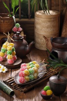 there are many small candies on the trays next to teapots and flowers