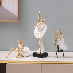 three gold and white figurines sitting on top of a table next to each other