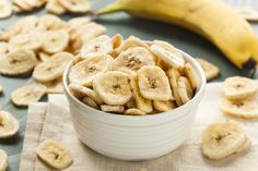 a white bowl filled with sliced bananas on top of a table next to a banana peel